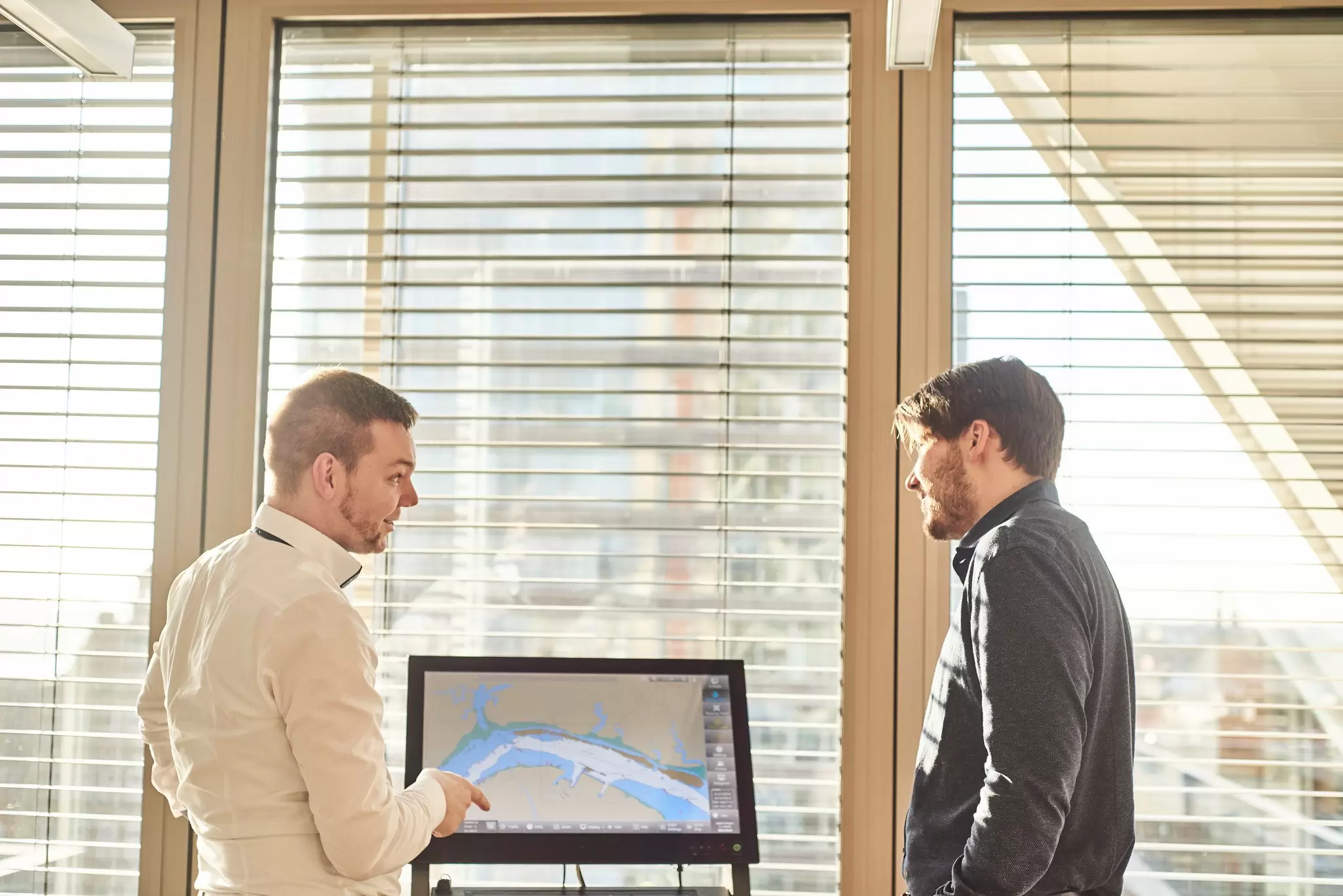 Image of two maritime professionals in an office with ECDIS displays behind them.