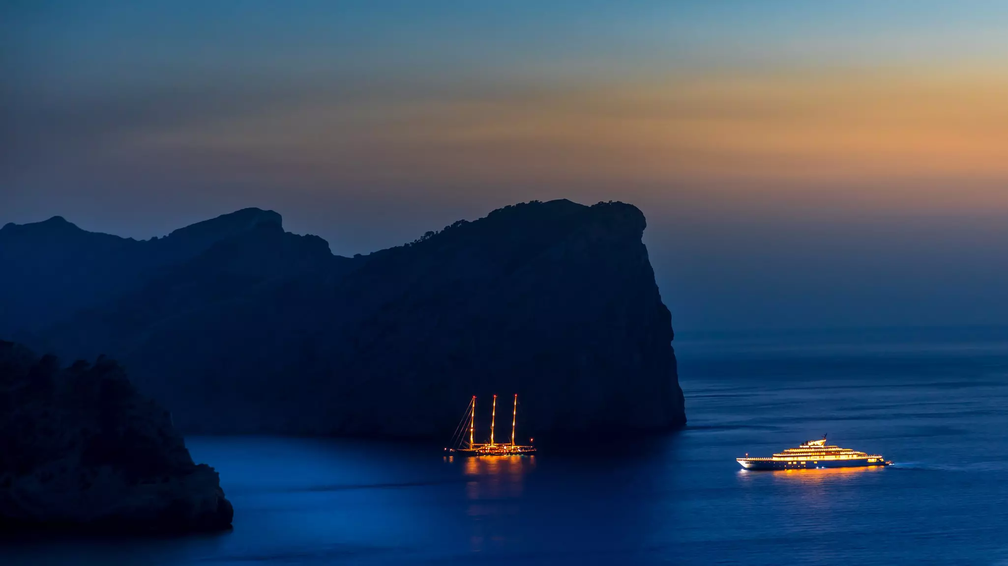 Two superyachts at anchor at night