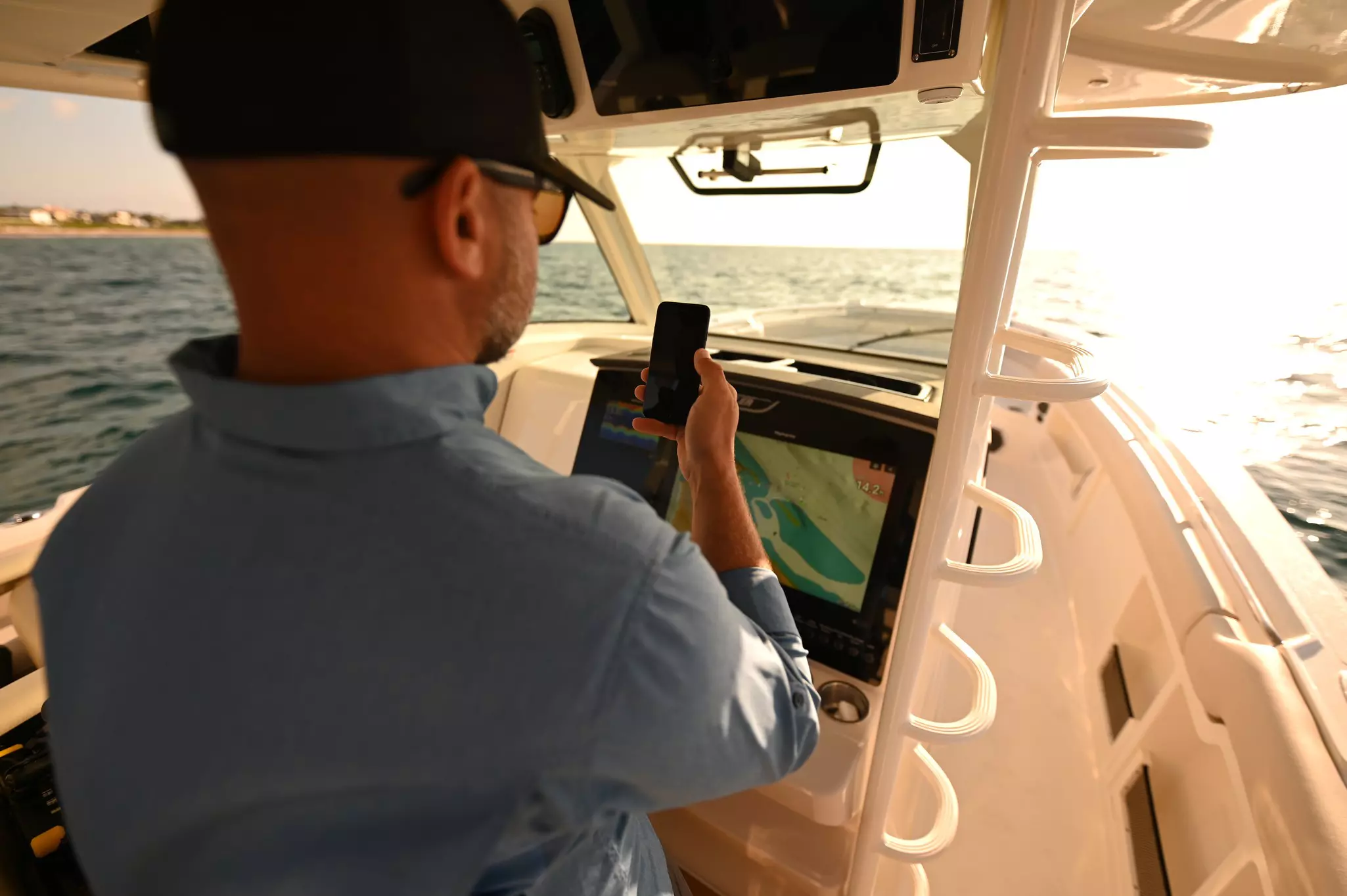 Schipper gebruikt een mobiele telefoon terwijl hij aan het roer van een boot staat