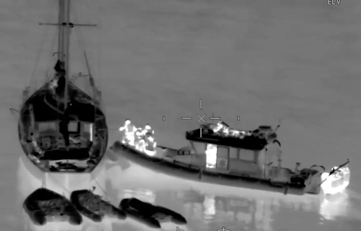 Thermal image showing security services on a patrol vessel approaching a sail boat.