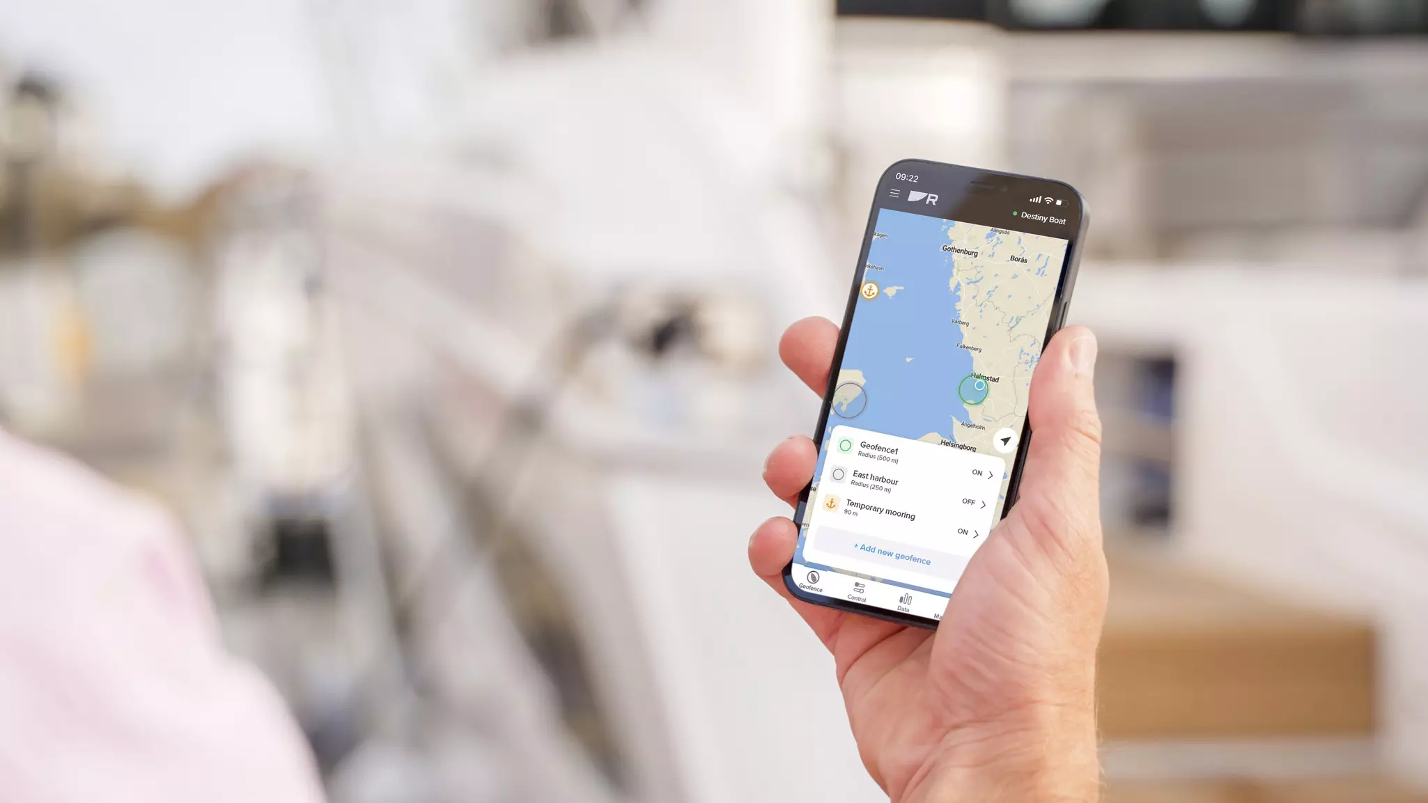 Boater holding an iPhone showing a geofenced boat on a marine chart.