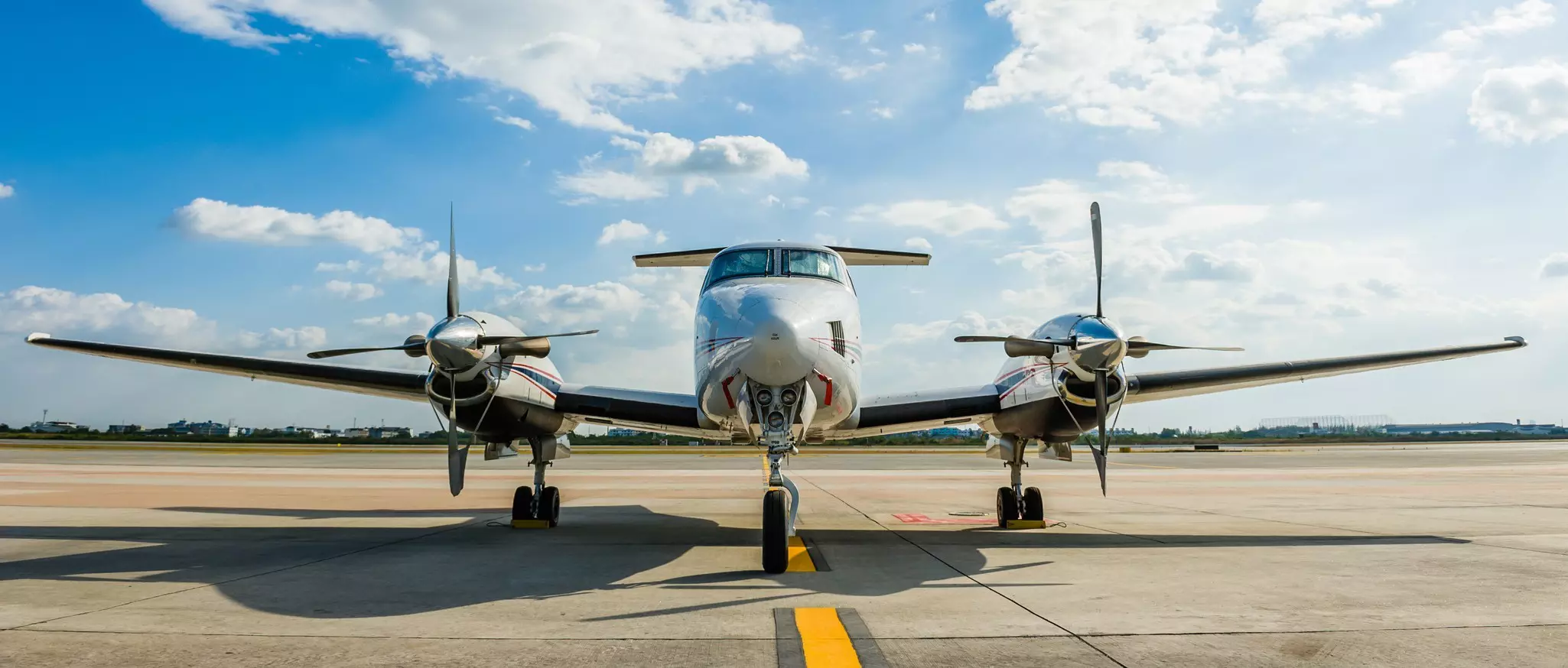Twin-engine propeller plan on runway under clear sky.